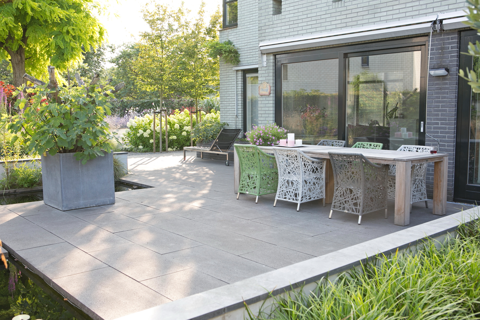 Terras met eettafel en witte rieten stoelen bij moderne woning