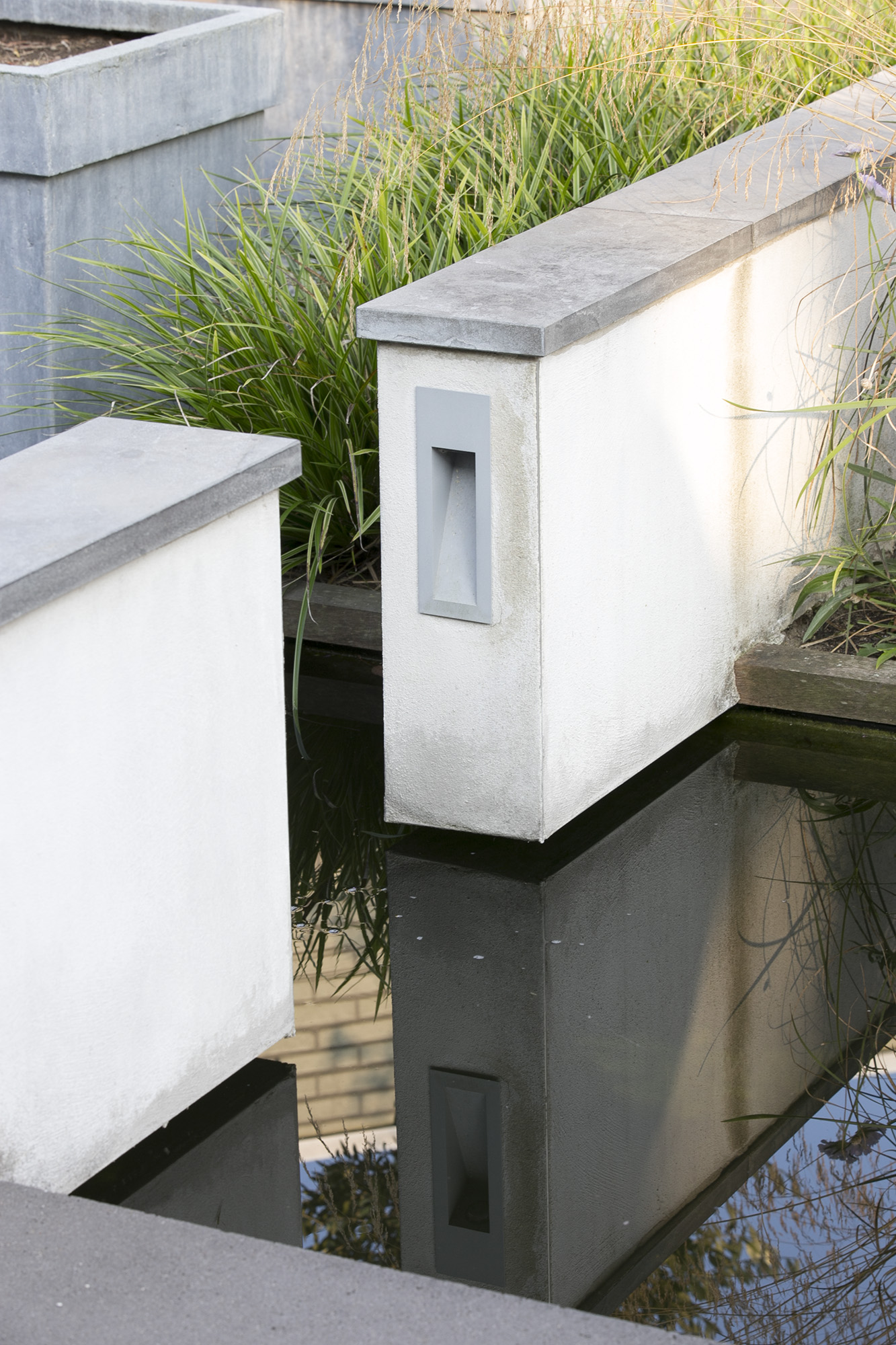 Detail van witte gestucte muurtjes met hardstenen afwerking en ingebouwde verlichting