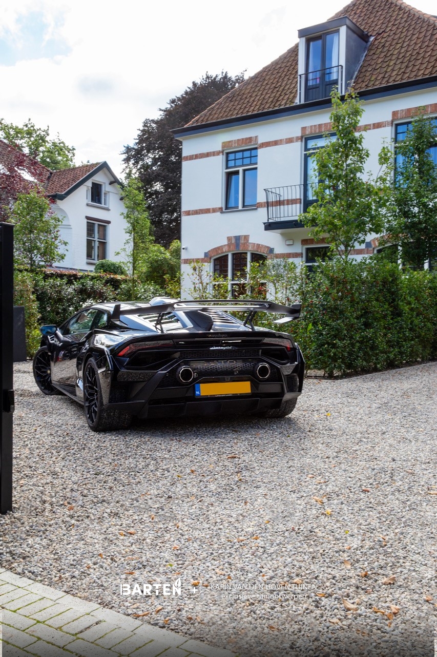 Voorzijde woning met luxe sportwagen op grindoprit