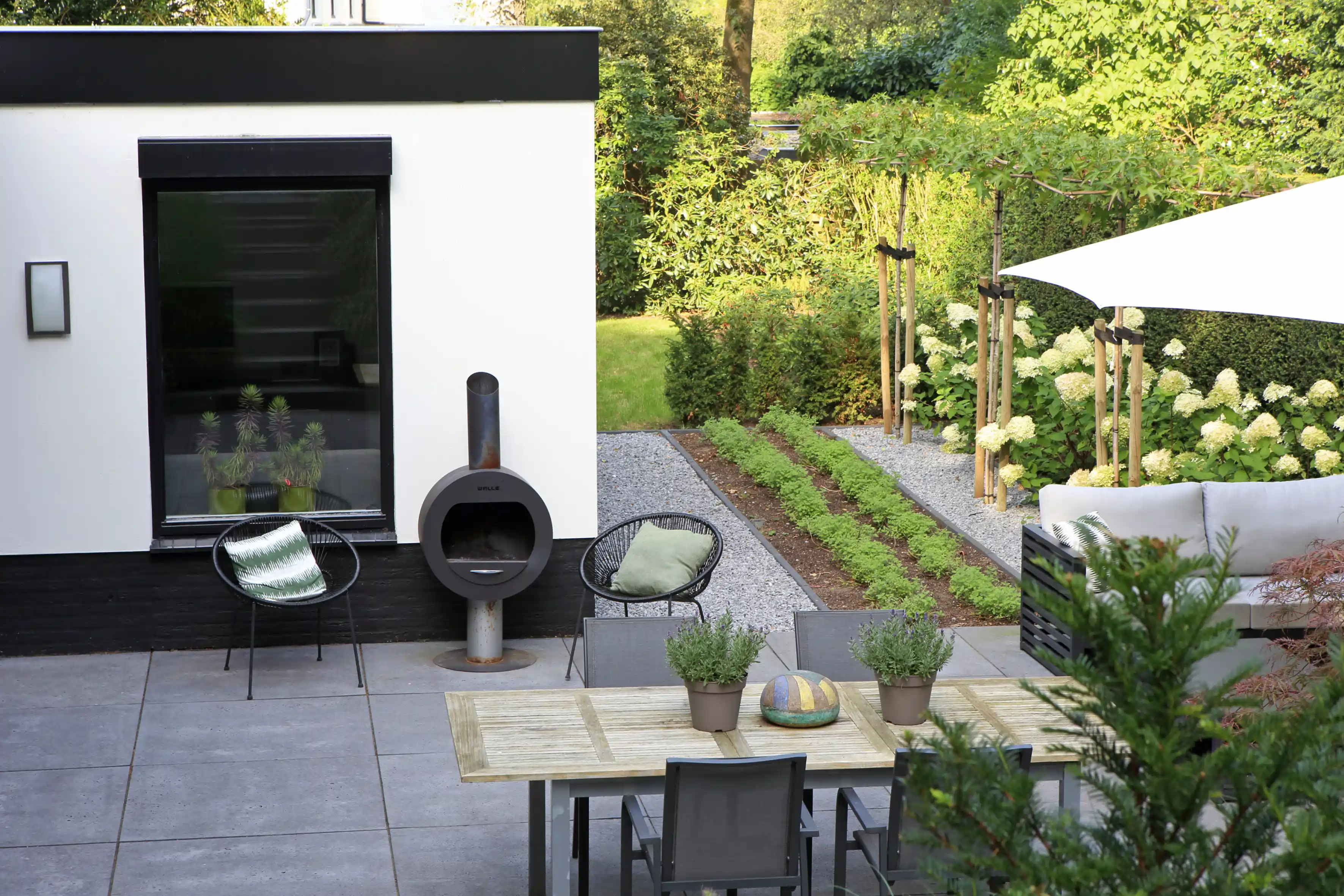 Moderne villa tuin met terras, buitenhaard en eigentijdse tuinmeubelen