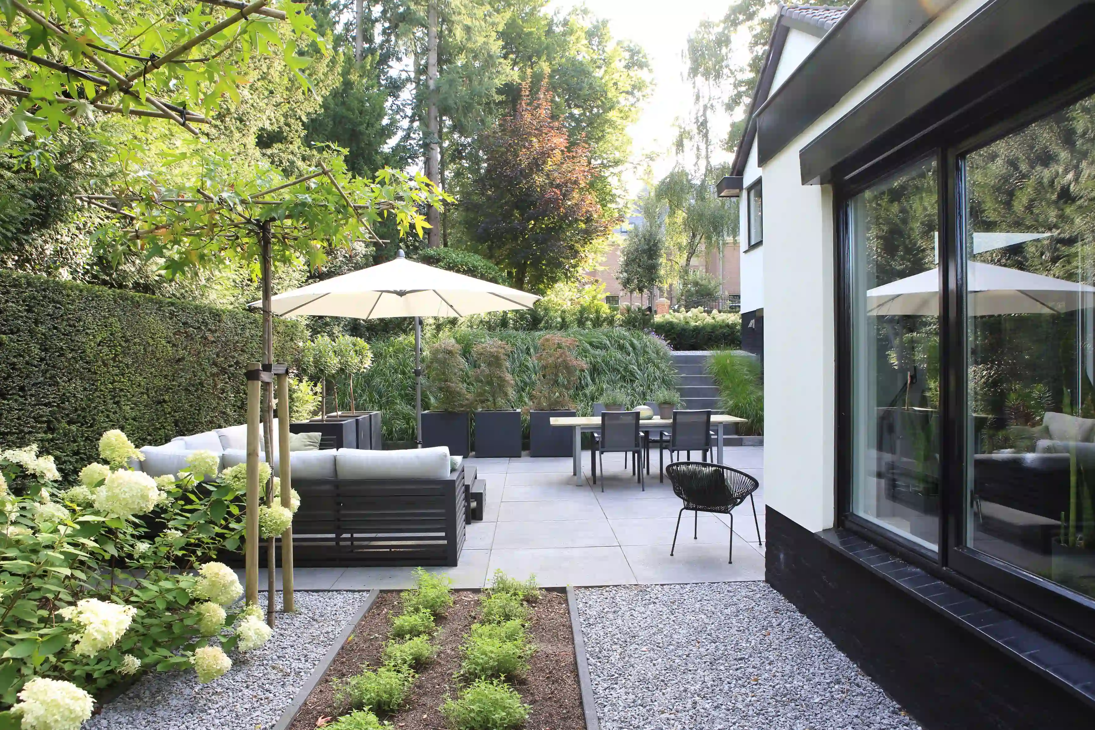 Modern huis met grote ramen en gestructureerde tuin