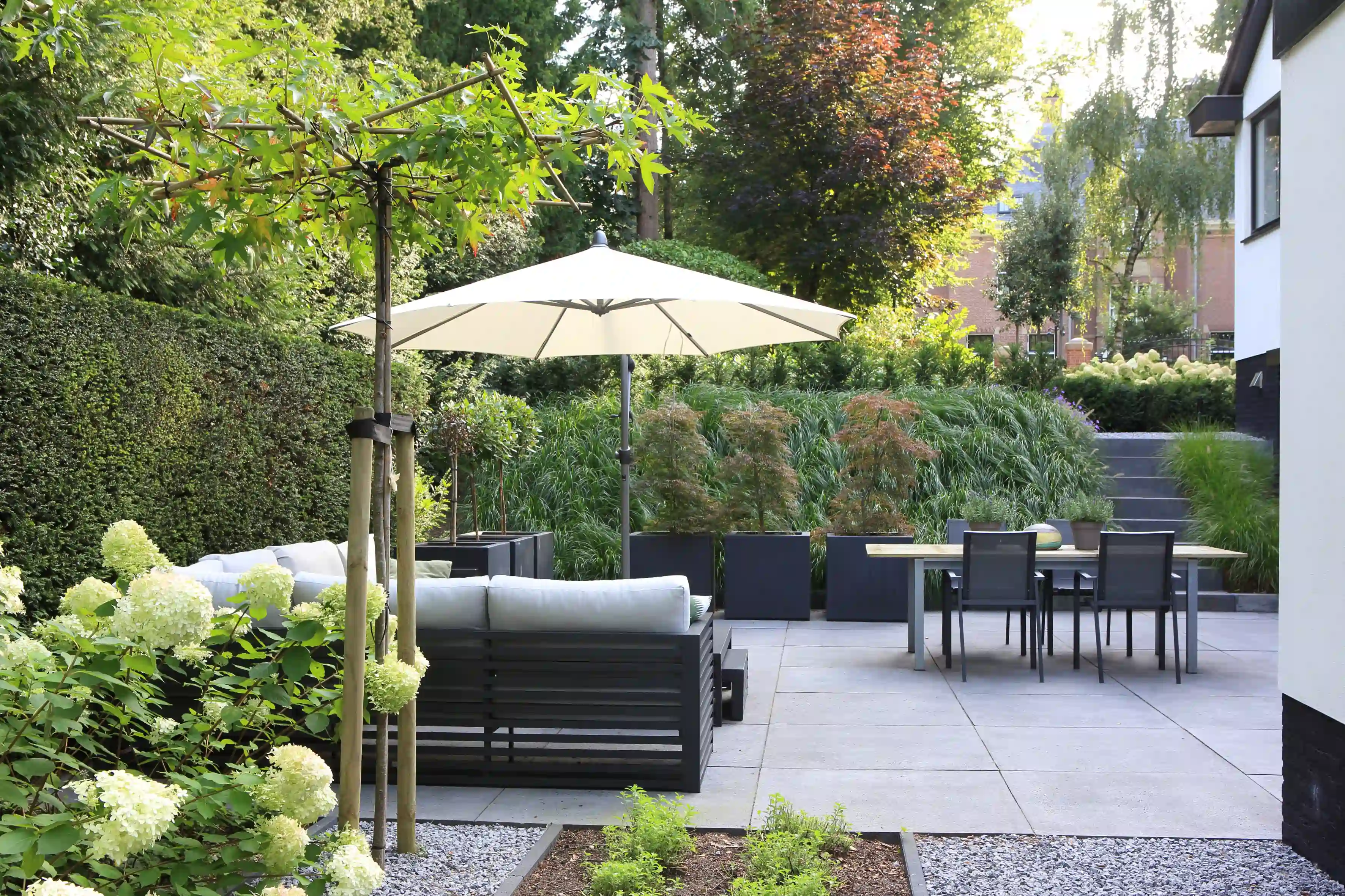 Buiteneetruimte met loungeset en Japanse esdoorns in plantenbakken