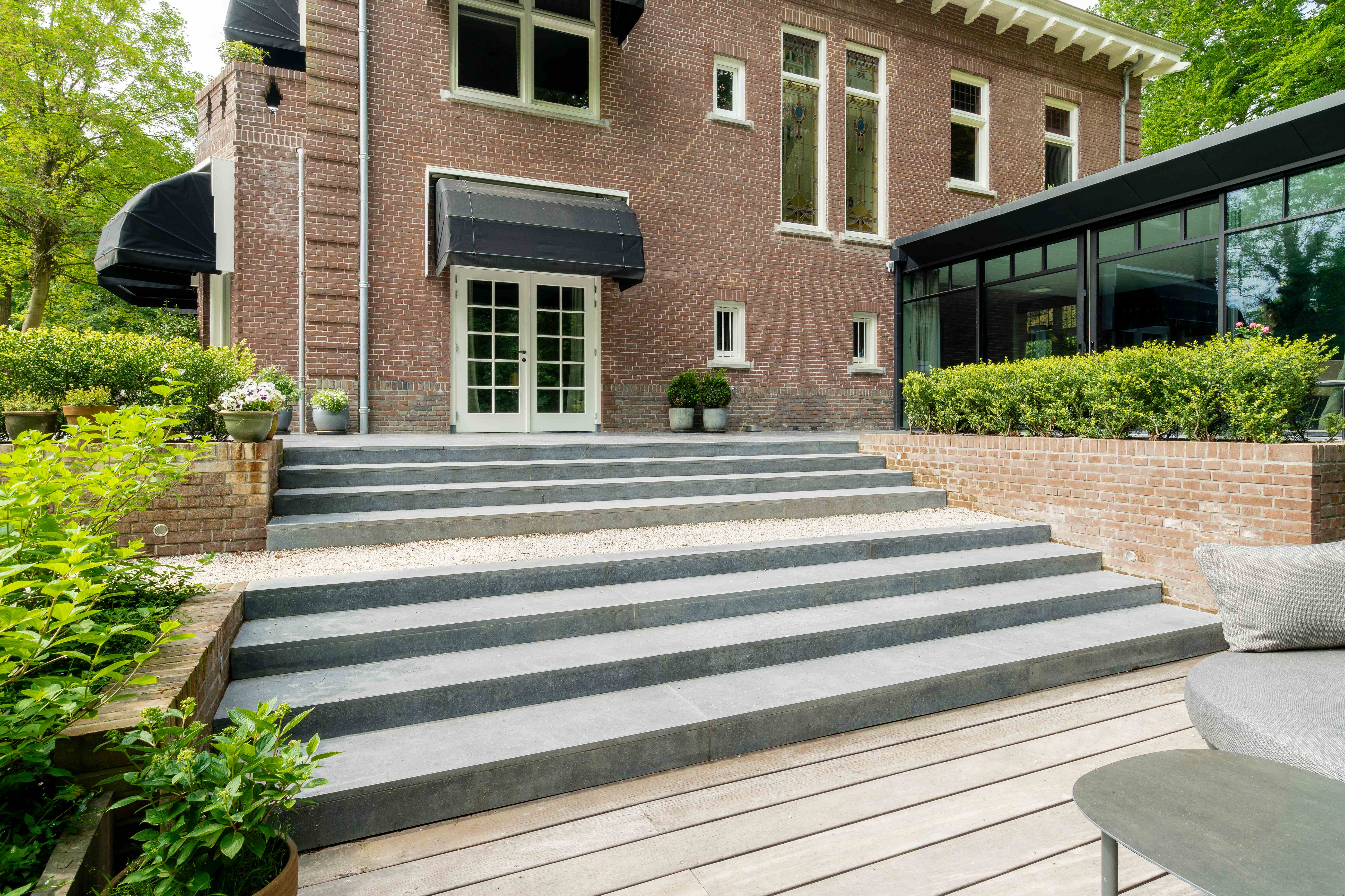 Overzicht van villa met moderne glazen uitbouw en stenen terras
