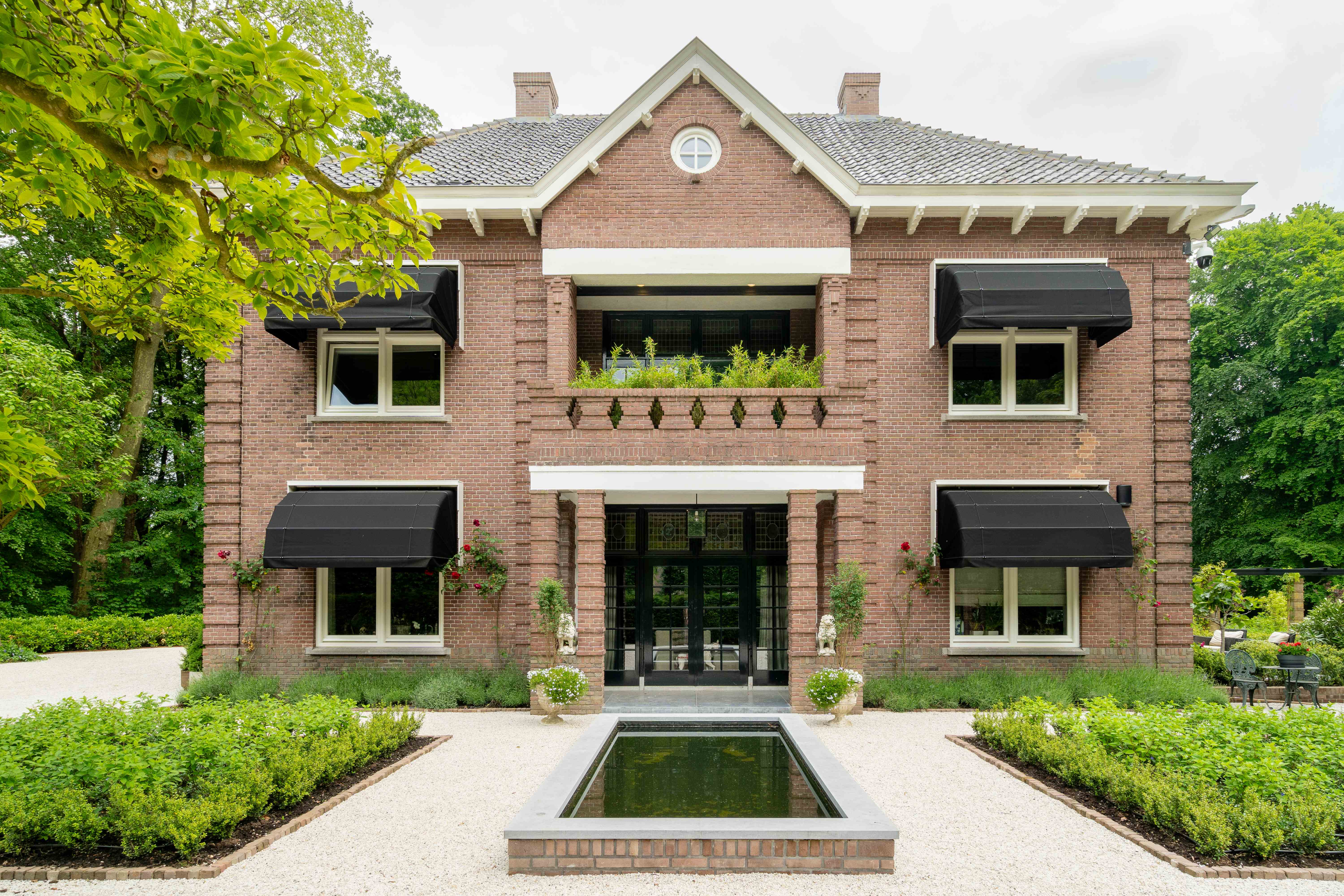 Voorgevel van villa met formele waterpartij en symmetrische beplanting