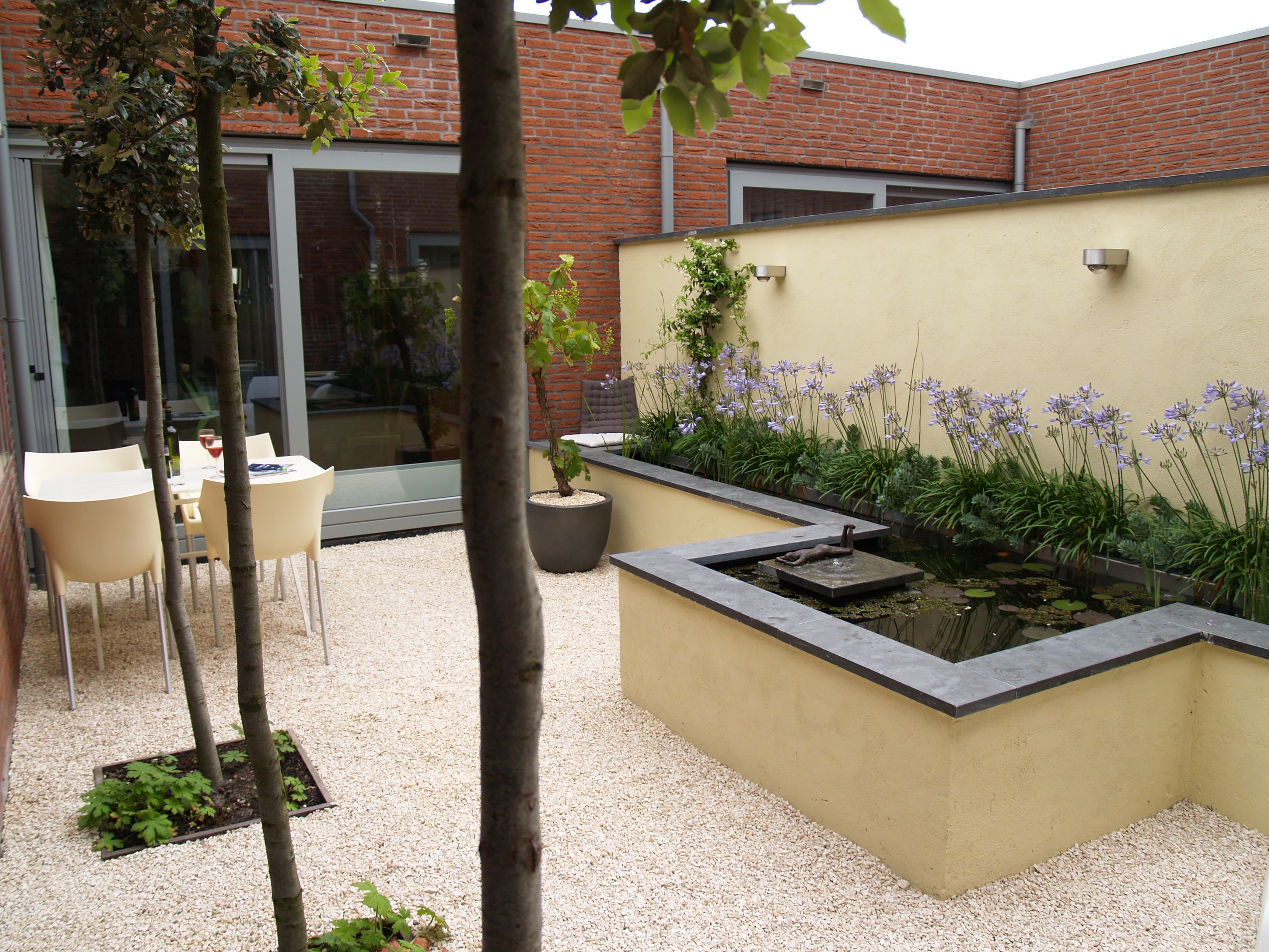 Eethoek met crème stoelen en verhoogde vijver met Agapanthus