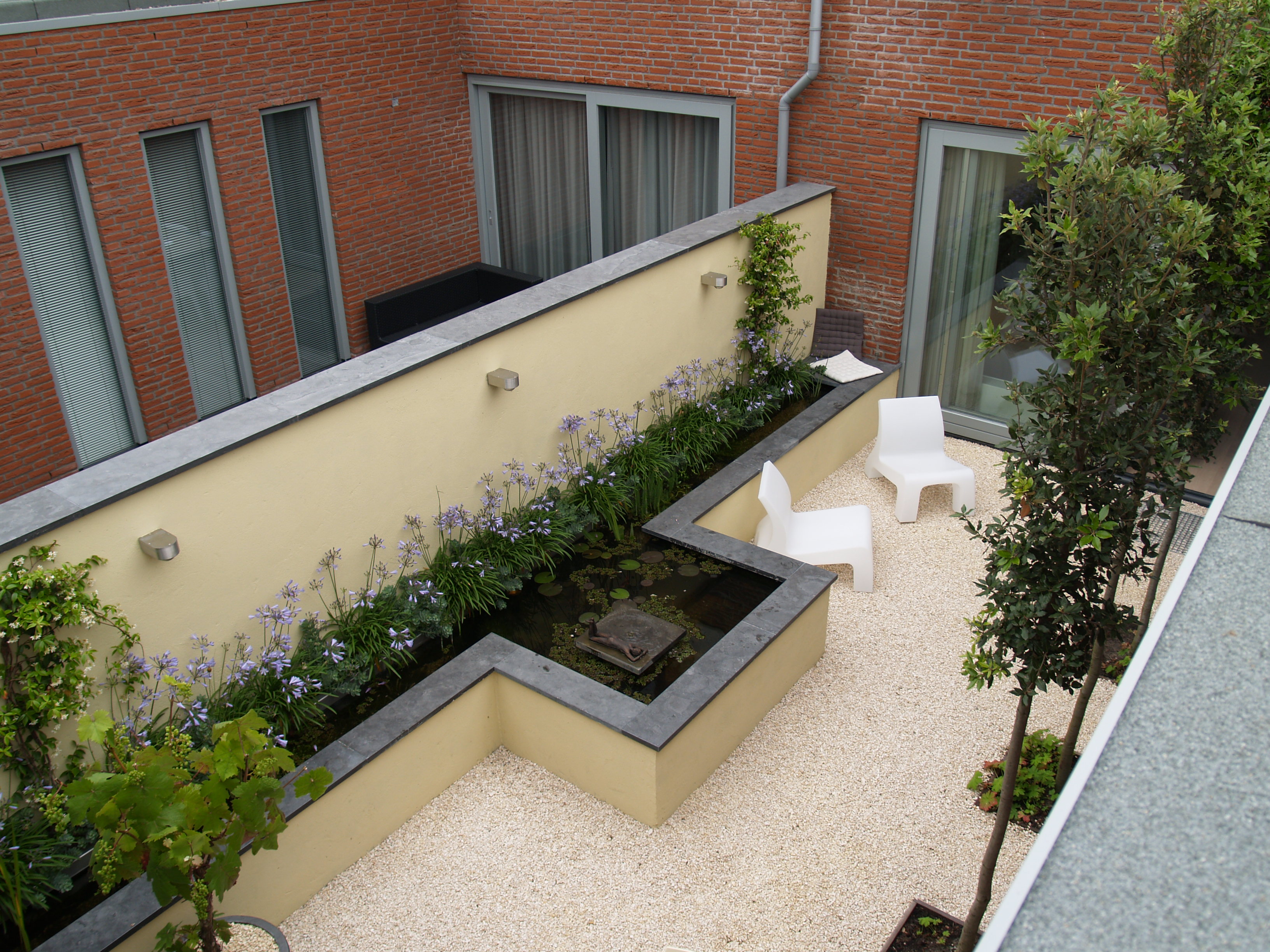 Luchtfoto met witte loungestoelen en verhoogde vijver