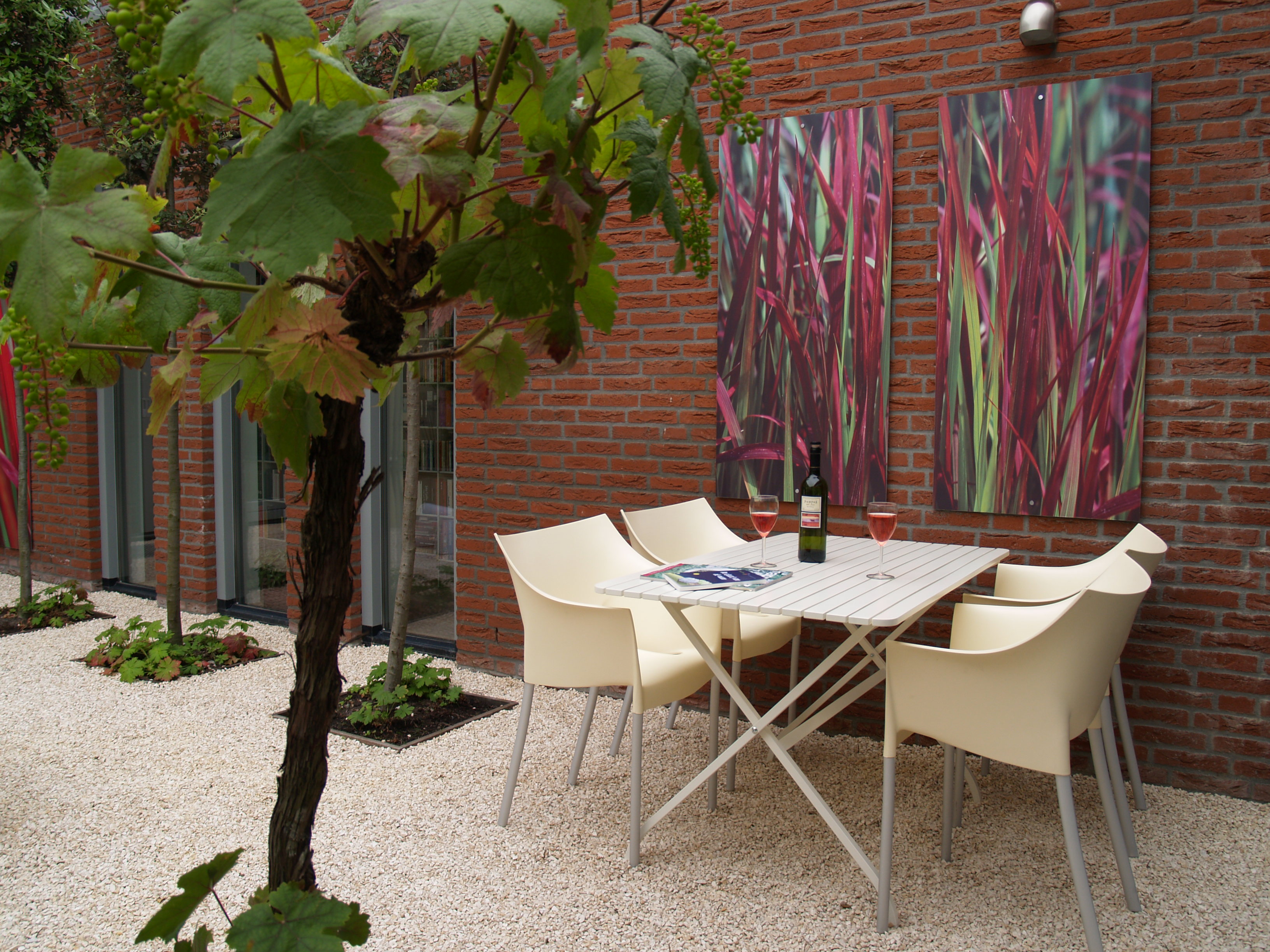 Eethoek met crème stoelen tegen bakstenen muur met kunstpanelen