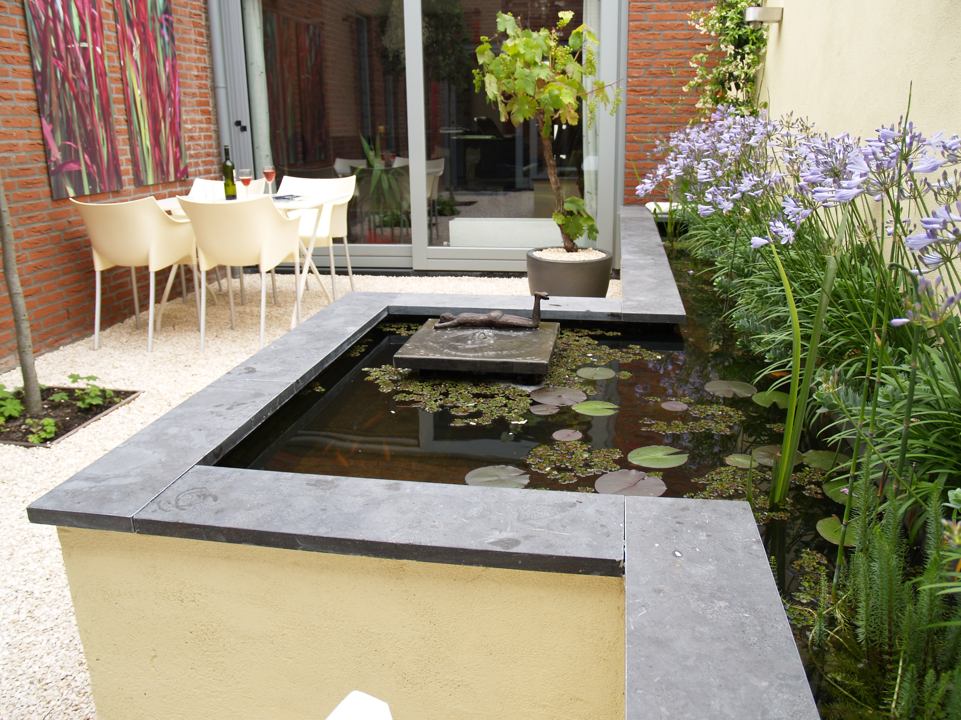 Close-up verhoogde vijver met sculptuur en waterlelies