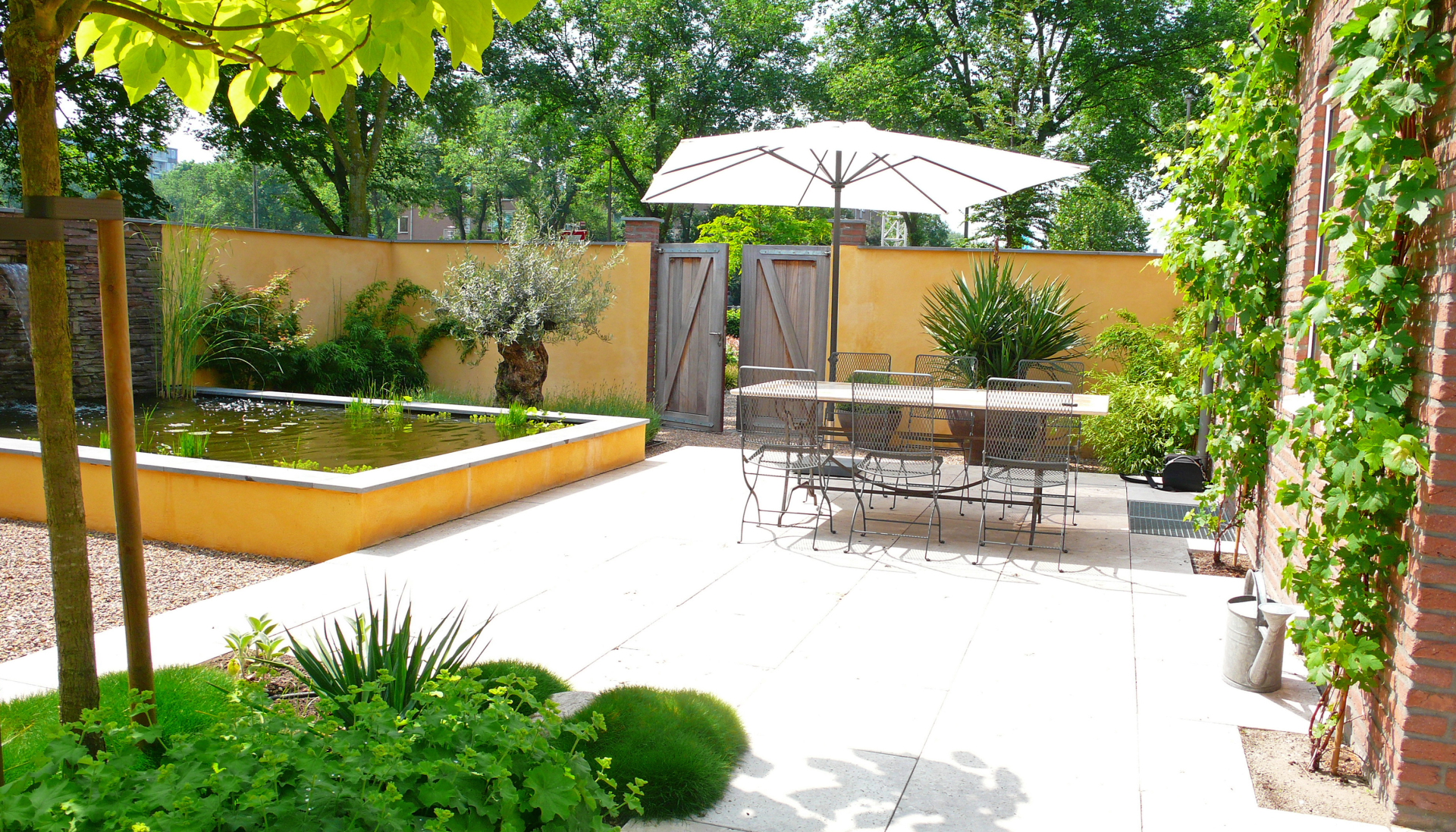 Mediterrane binnentuin met okergele stucmuren en verhoogde vijver