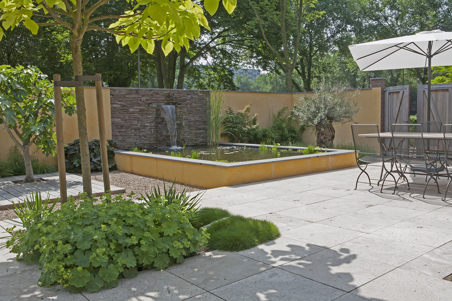 Verhoogde vijver met waterval, okergele muren en zithoek